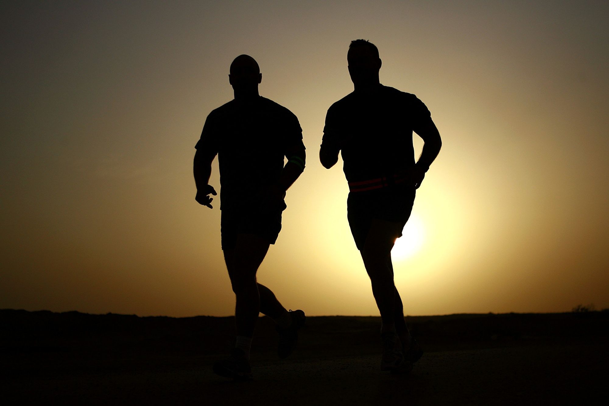 two men jogging in the sunset
