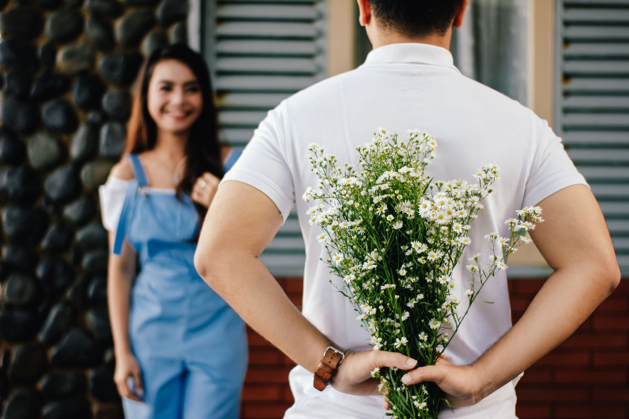 man surprising woman with flowers